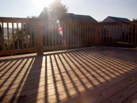 Sunlight on a wood deck wtih railings.